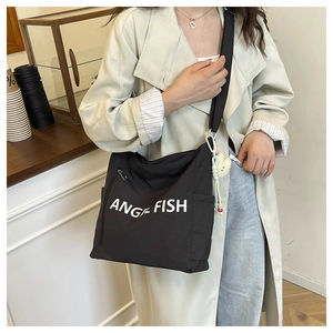 Detail view of black canvas shoulder bag with Angel Fish print and cute doll keychain