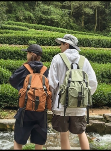 Mochilas de nailon impermeable en naranja jengibre y verde haba en un jardín de té verde