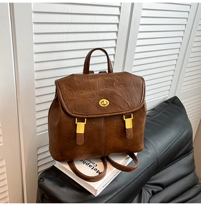 Detail of vintage dark brown leather backpack with gold twist lock and adjustable straps