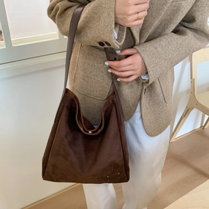 Detailed view of dark brown suede tote bag featuring iconic white four-corner stitching