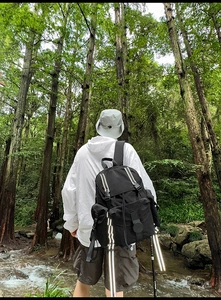 Toma exterior de una mochila funcional negra con correas reflectantes en un entorno forestal
