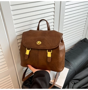 Detail of vintage brown leather backpack showing gold twist lock and fine grain texture