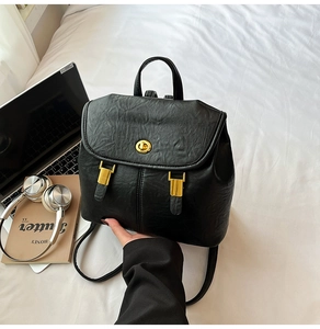 Close-up of black lychee texture leather backpack with golden twist lock and metal buckles