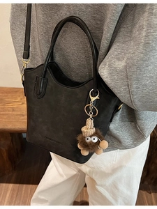 Black matte leather bucket bag with wavy edge design and cute plush charm on a model