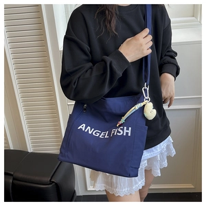 Detail of dark blue nylon tote bag featuring Angel Fish print and plush heart charm