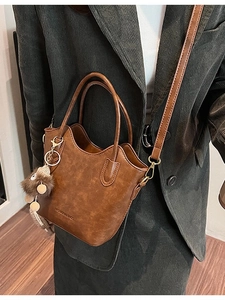 Retro brown textured PU leather bucket bag with wave edge and plush charm on shoulder strap