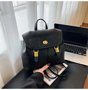 Detail of black faux leather backpack featuring golden metal twist lock and minimalist design