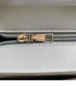 Detail of smooth gold metal zipper and stitching on the light gray leather backpack