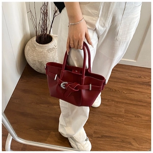 Détail du sac seau plissé rouge foncé avec boucle argentée et texture en cuir mat