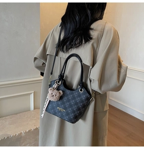 Dettaglio della borsa a tracolla a scacchi grigio scuro con ciondolo a orsetto e foulard di seta