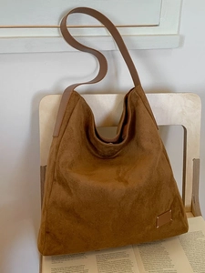Retro brown suede hobo bag with wide shoulder strap and large capacity on wooden chair