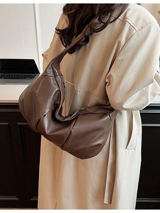 Fashionable dark brown pleated crescent shoulder bag in soft leather on a model