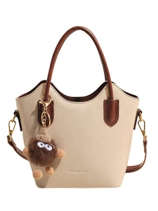 Chic cream bucket bag with brown handles and a cute monster charm for women