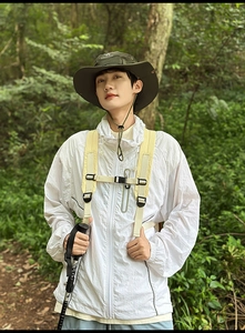 Detail of white hooded sports jacket and green sun hat in a forest hiking scene
