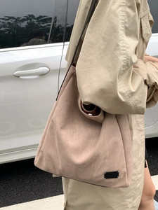 Large beige suede tote bag for women with minimalist shoulder strap in a street style shot