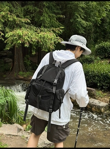 Primer plano de mochila táctica negra de nailon con hebillas metálicas en el bosque