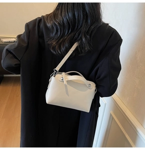 Detailansicht einer cremefarbenen Ledertasche mit silbernen Nieten und feiner Ledertextur