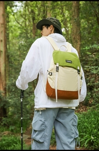 Outdoor color-block backpack detail featuring green and khaki panels in forest setting