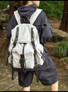 Vista exterior de una mochila de nailon gris claro con correas y hebillas negras