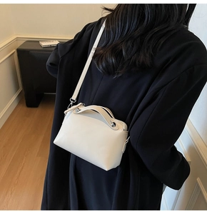 Modell mit cremefarbener Ledertasche mit silbernen Nieten zu einem schwarzen Blazer