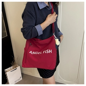 Detail of red canvas tote bag with white lettering and heart keychain charm accessory