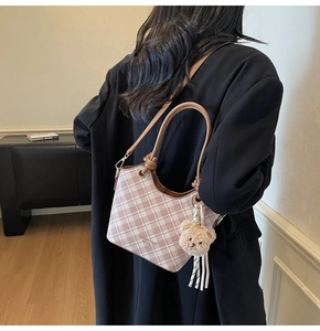 Vista posteriore di una modella con borsa a secchiello a quadretti rosa e bianchi e orsetto