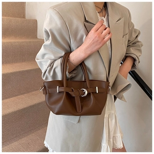 Détail d'un sac seau plissé marron avec boucle en croissant d'argent sur similicuir
