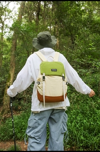 Outdoor hiking backpack in cream and green nylon shown in a forest setting