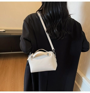 Detail einer weißen Lederhandtasche mit Nietengriff und Schultergurt, schräg getragen
