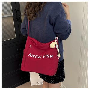 Detail of red canvas shoulder bag with Angel Fish print and yellow moon plush charm