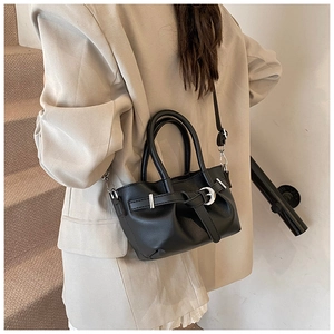 Détail du sac seau noir plissé avec boucle en métal porté sur un tailleur beige