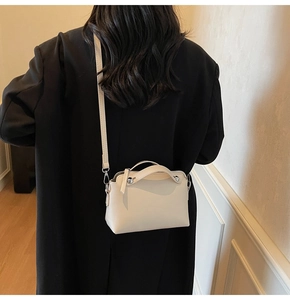 Mini cremefarbene Umhängetasche an Model mit schwarzem Mantel für den täglichen Look