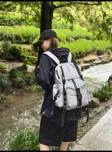 Detalle de mochila funcional gris claro con correas ajustables para viajes al aire libre