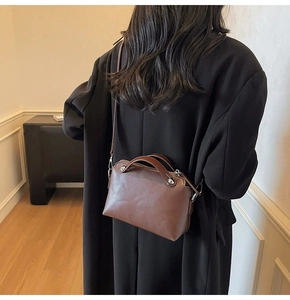 Detailansicht der dunkelbraunen Lederhandtasche mit Silbernieten und Schultergurt