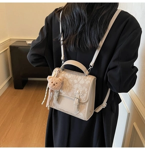 Detail of cream vintage backpack with floral jacquard texture and bear charm