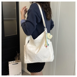 Detail of white canvas tote bag with Angelfish logo and cute yellow plush chick charm