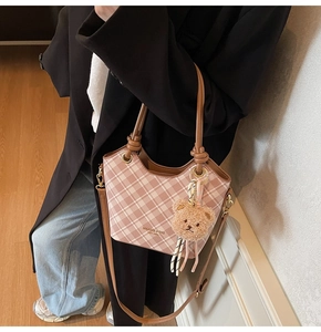 Dettaglio della borsa a secchiello a quadretti rosa con manico in pelle e ciondolo