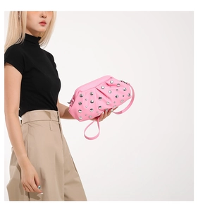 Dettaglio della borsa a pieghe rosa con borchie indossata da una modella in nero