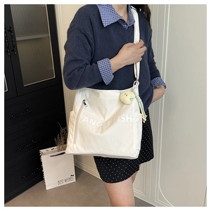Detailed shot of white canvas crossbody bag with Angel Fish print and cute plush fish charm