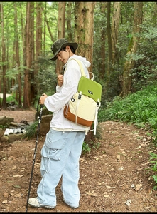Outdoor hiker carrying a color-block waterproof backpack in a lush green forest setting