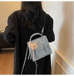 Detail of light blue lace shoulder bag with decorative bow and cute bear keychain