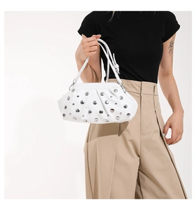 Dettaglio della borsa bianca con borchie argentate e texture a pieghe indossata dalla modella