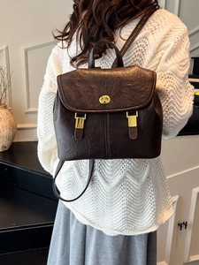 Vintage dark brown faux leather backpack with gold buckle shown on a model's back