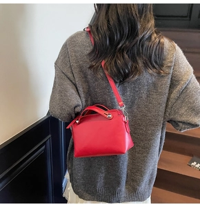 Detail der roten Boston-Tasche aus Leder mit Nieten und Schultergurt an einem Model