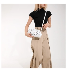 Détail du sac nuage blanc orné de rivets porté par un mannequin avec bandoulière fine