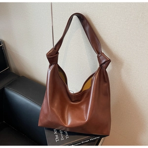 Close-up of brown soft leather tote bag featuring a signature large knot on shoulder strap