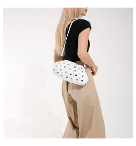 Détails des clous argentés sur le sac croissant en cuir blanc porté par un mannequin
