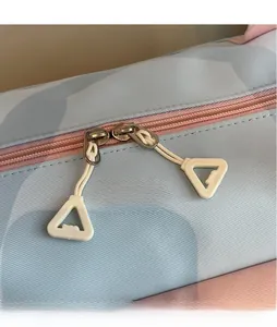 Dettaglio del tessuto twill azzurro con doppia cerniera rosa e tiranti bianchi