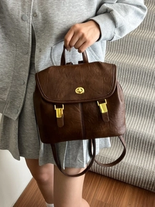 Retro dark brown leather backpack for women featuring a top handle and gold metal hardware