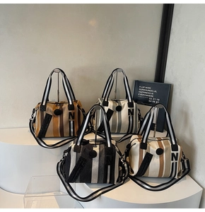 Detail of four striped canvas Boston bags on display with handles and crossbody straps